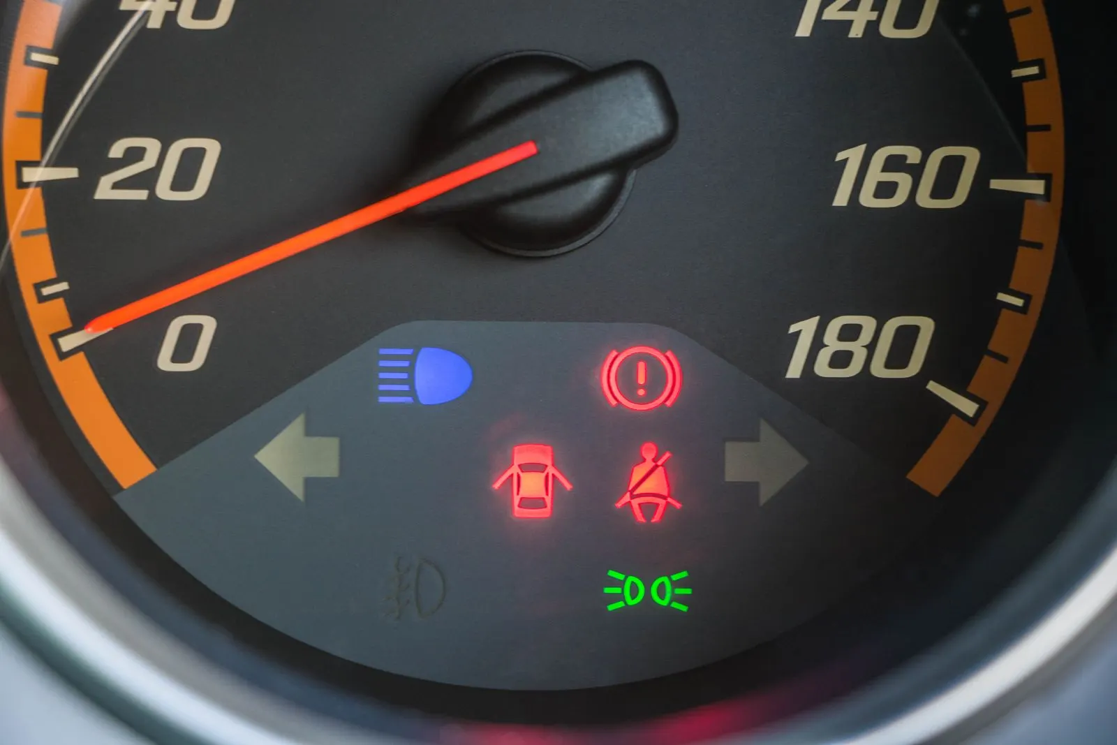 Car instrument cluster with the red brake system warning light lit, a red circle with an exclamation mark, next to door and seat belt warnings
