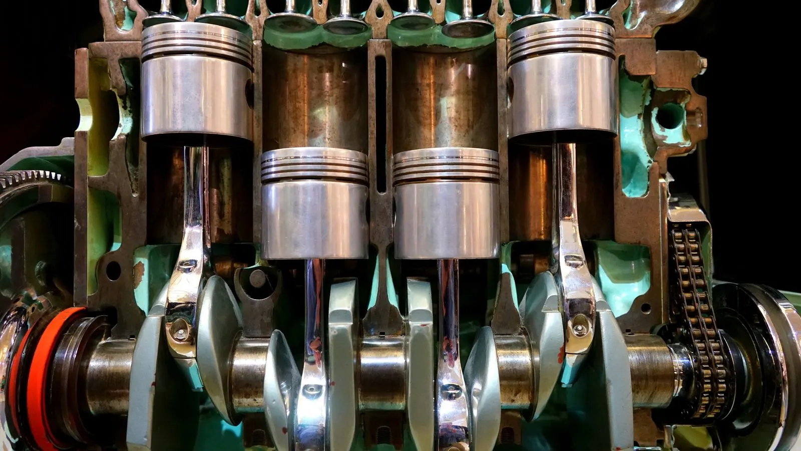 Cutaway of an engine showing four pistons on connecting rods attached to the crankshaft below them