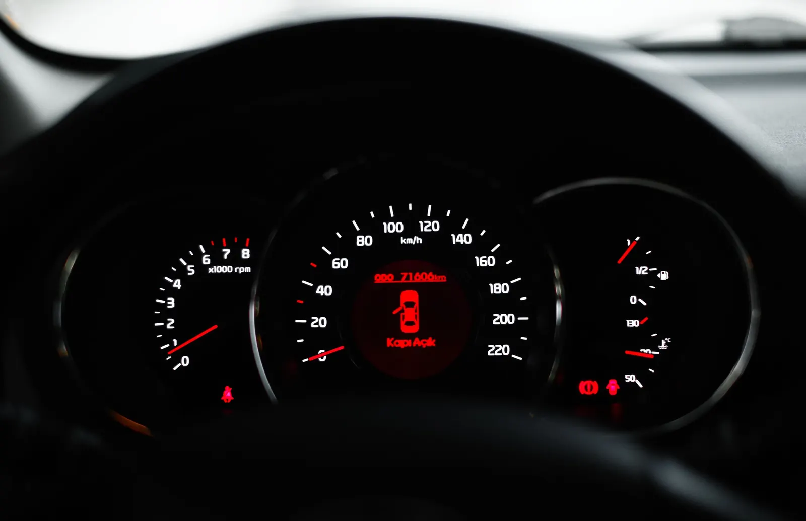 A lit instrument cluster at night with a red warning message in the center display