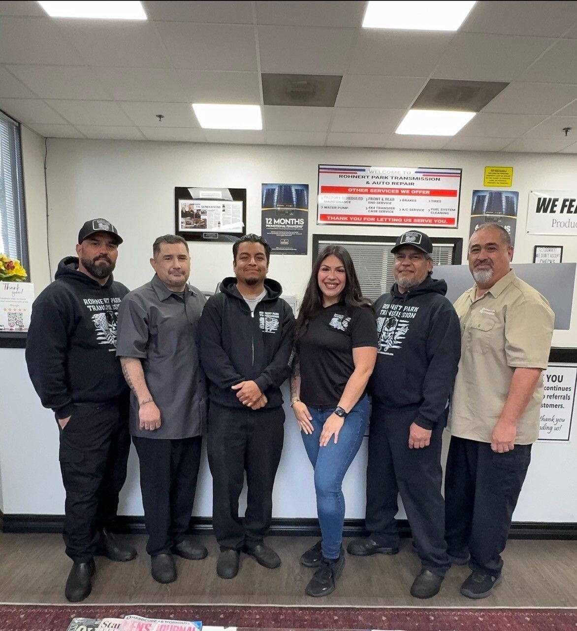 The Rohnert Park Transmission team standing in front of the shop services board, which lists 4x4 transfer case service