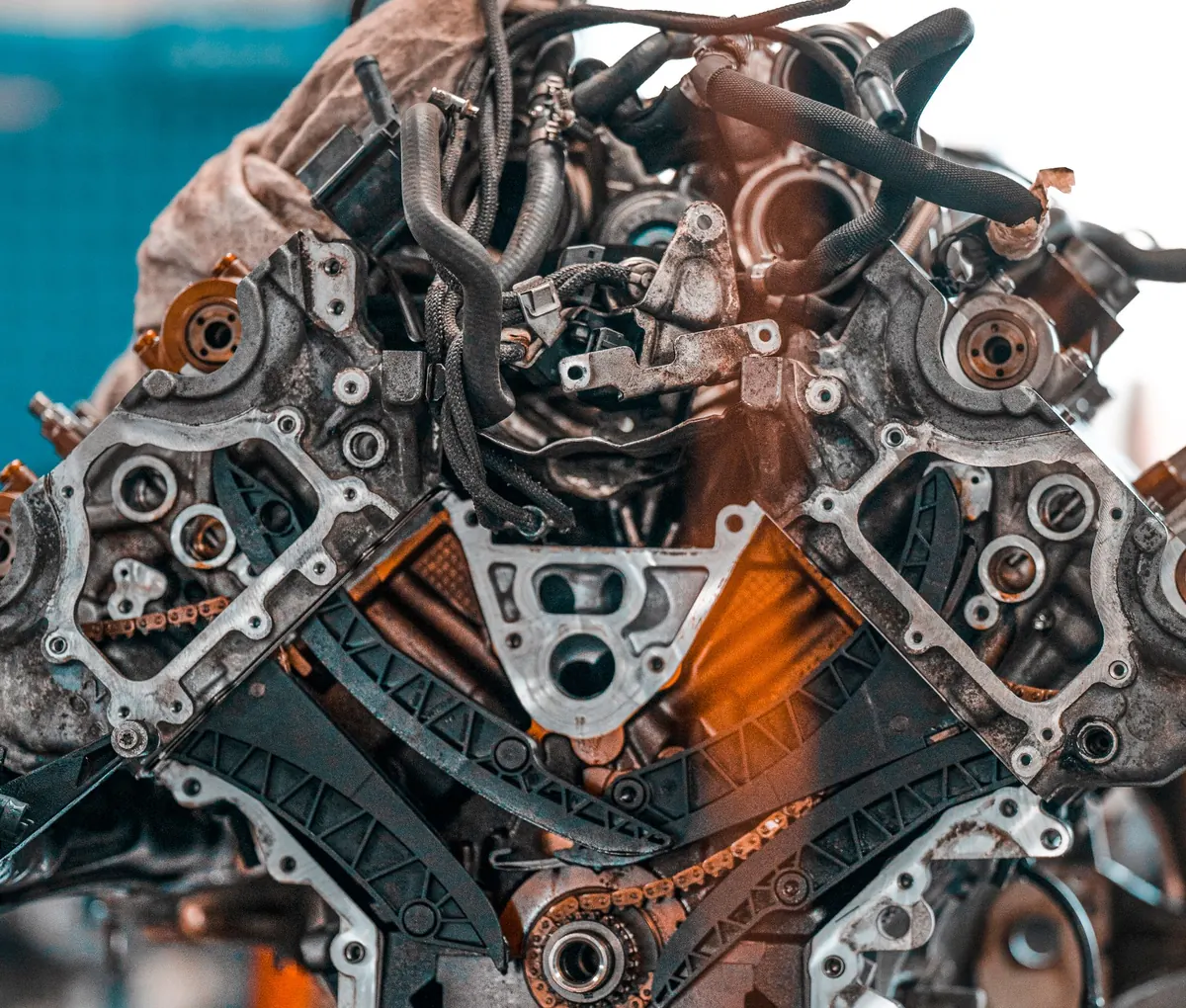 Front of a V-shaped engine on a stand with the timing cover removed, showing the timing chains, the black plastic chain guides and the sprockets on both cylinder banks